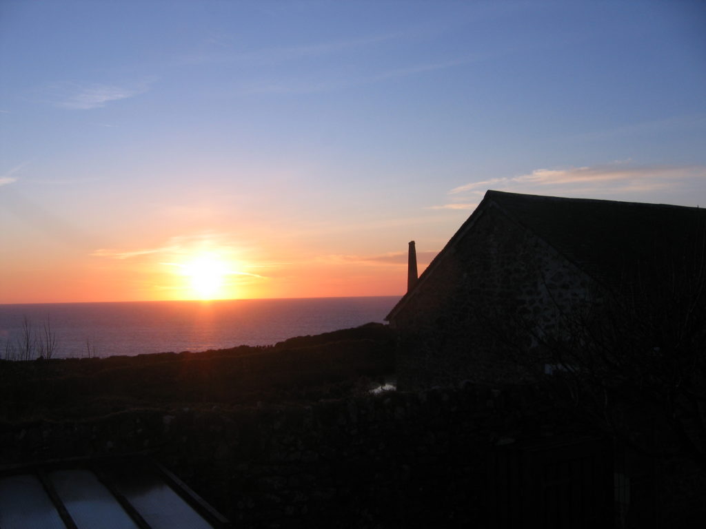 photo of sun setting into the sea as seen from the garden of a cottage in Cornwall